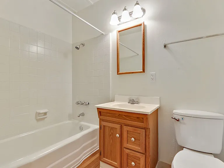 Bathroom with tub and shower combo, single round vanity with wood texture, wood-style flooring