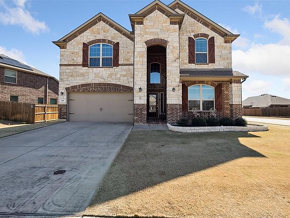 French country style house with a front yard, brick siding, driveway, and an attached garage