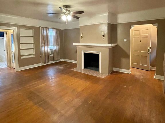 Main Living Room with front entrance at left, faux fireplace, lot's of windows, built in book shelves and large closet.