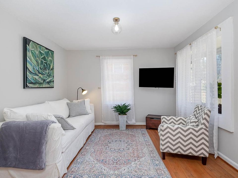 Living room with sunny bay window, Crate and Barrel sleeper sofa and Roku TV on an extension arm for easy access for gamers.