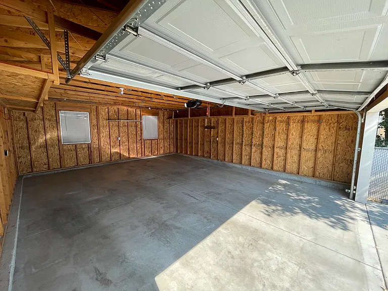 Large 2 car garage with lots of extra storage, hooks for bikes, built in shelving for standard black totes along both walls
