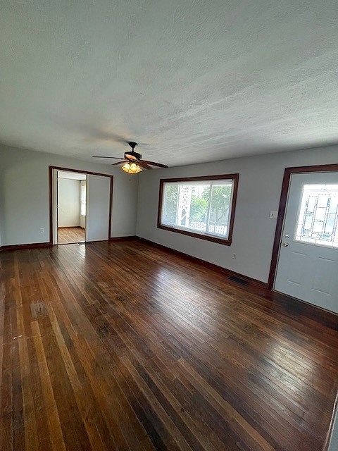 Living room with hardwood and ceiling fan. 18'10" x 11'11" Large picture window and steel front door with decorative glass.