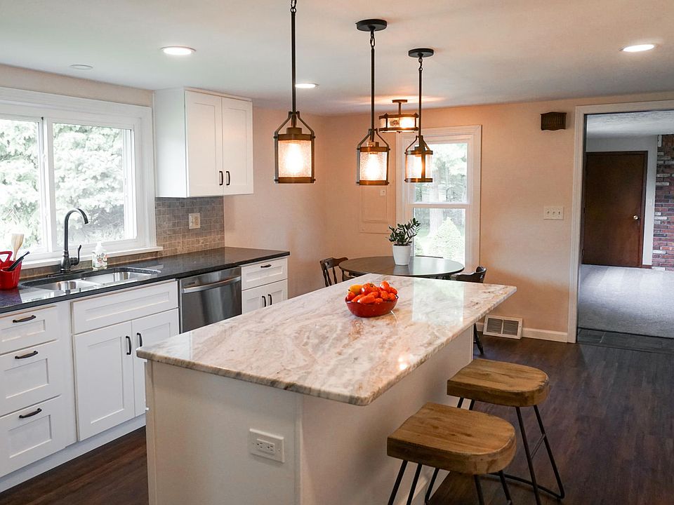 Large, brand-new kitchen with new stainless appliances, granite countertops, and wood grain flooring.