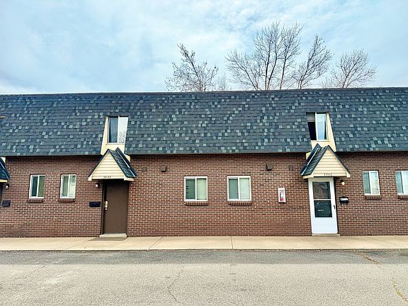 Charming brick townhouse exterior with modern windows and distinctive roof design, ideal for comfortable urban living.