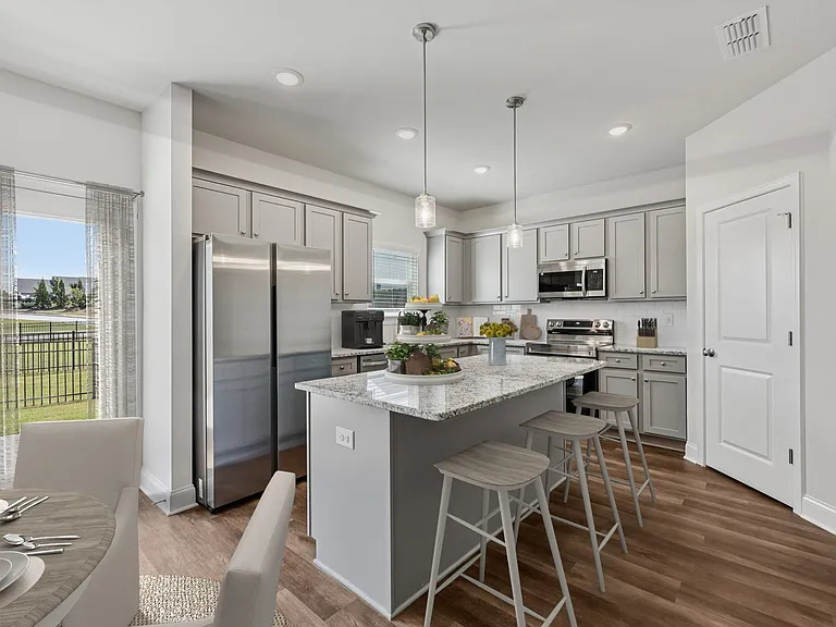 A modern kitchen showcasing a granite countertop island with bar seating and premium stainless steel appliances.
