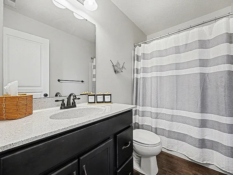 This well-maintained bathroom features contemporary finishes, ample counter space, and a full-size tub and shower. Fresh, neutral decor creates a spa-like atmosphere, giving guests a relaxing space to begin and end each day.