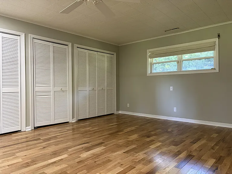 Spacious primary bedroom featuring beautiful hardwood floors, generous closet space, and direct access to the en-suite bathroom.