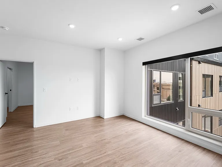 Bright and spacious room with elegant wooden flooring, large window with urban view, and modern recessed lighting. Bright and spacious room with elegant wooden flooring, large window with urban view, and modern recessed lighting.