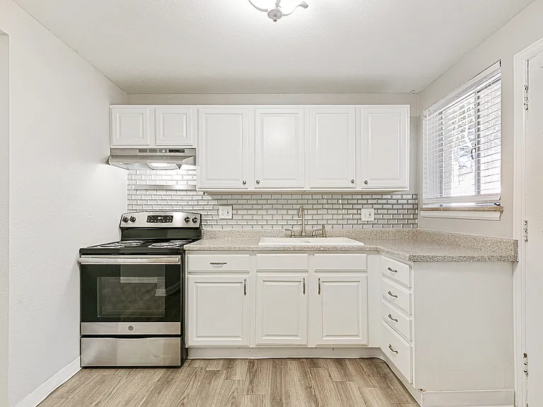Bright and modern kitchen with sleek white cabinetry, stainless steel appliances, and elegant tile backsplash.