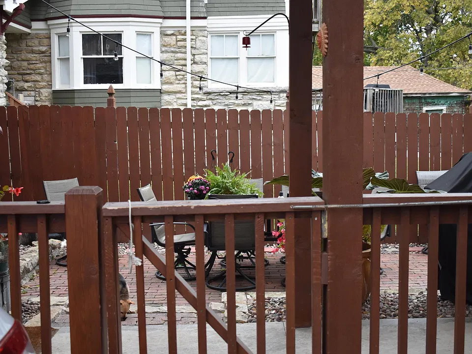 Gate from driveway into property - looking at shared patio area and gas grill