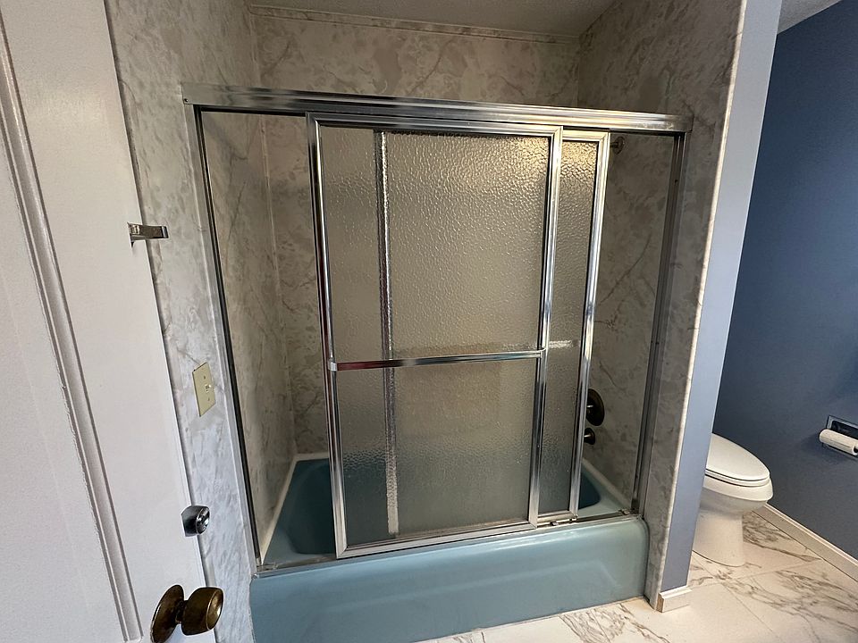 Shower with sliding doors. Tile flooring and linen closet facing (not shown)