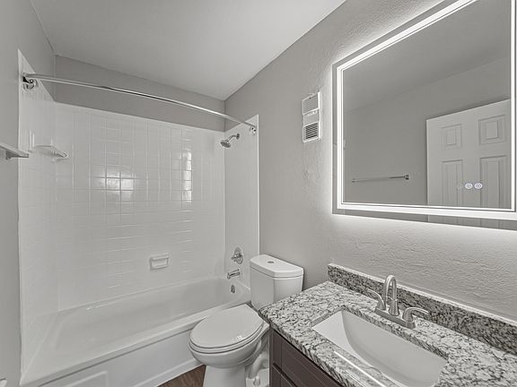 Updated two-bedroom apartment bathroom with granite vanity and modern lighting