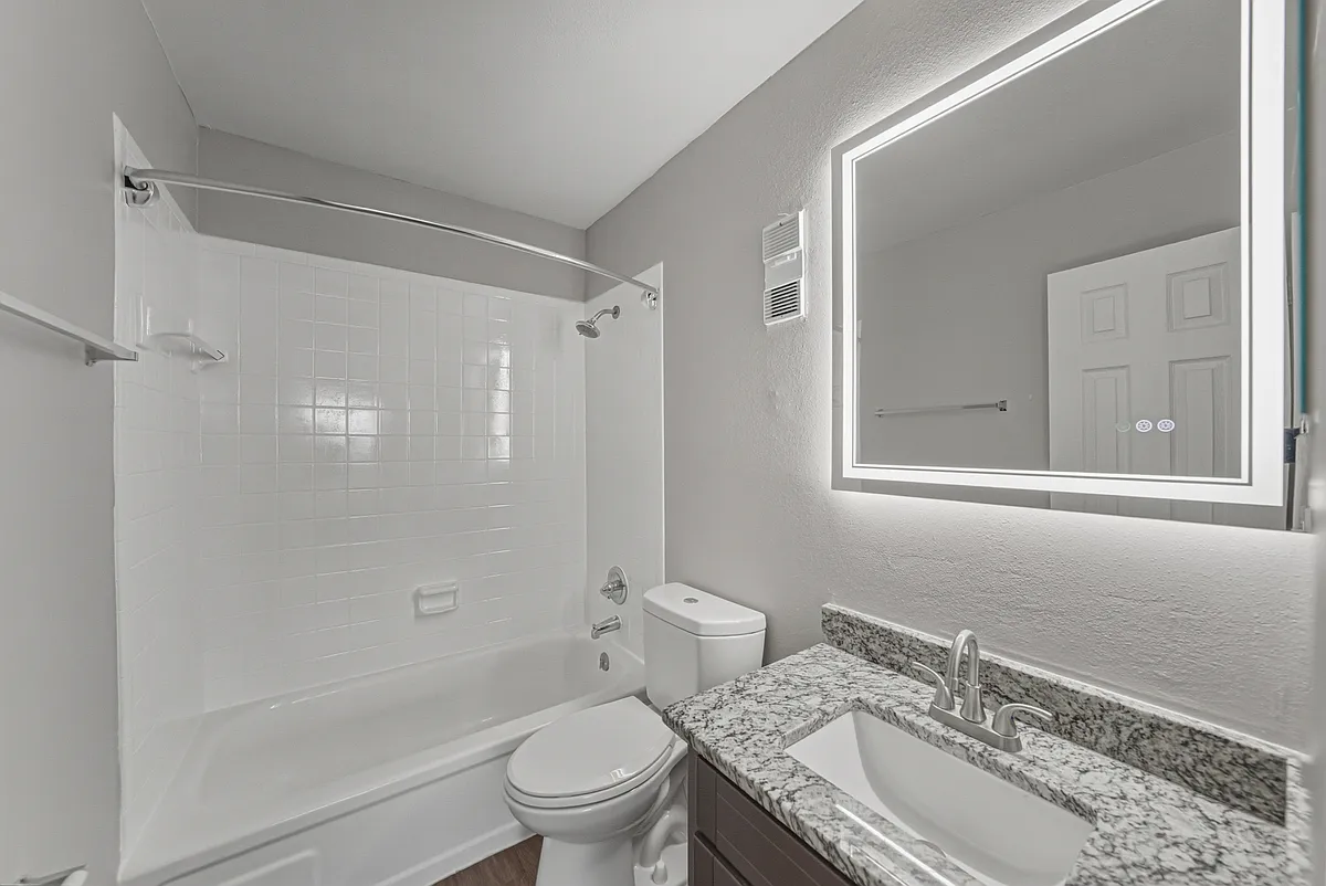 Updated two-bedroom apartment bathroom with granite vanity and modern lighting - Magnolia Apartments