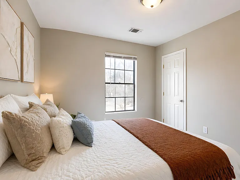 Comfortable bedroom with a full-size bed, neutral finishes, and a window for natural light, plus a convenient closet door.