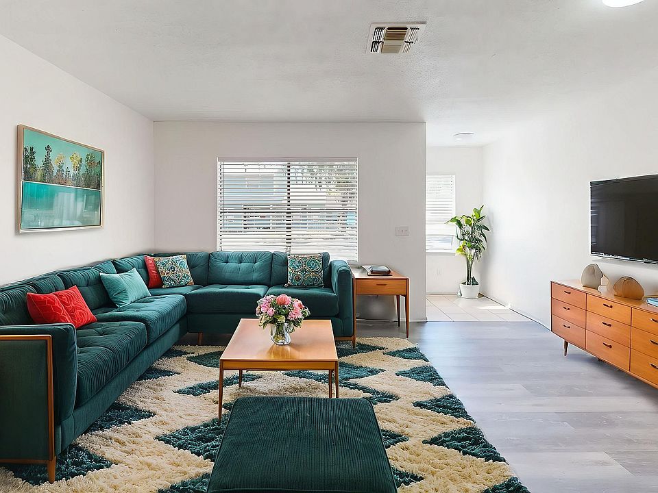 Bright and inviting living room with a chic teal sectional sofa, mid-century modern furniture, and elegant decor, perfect for relaxation and entertainment.