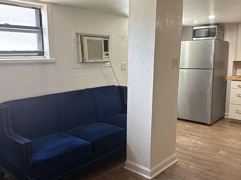Open living area with durable wood-look flooring, comfortable seating, and direct access to the adjacent kitchen.