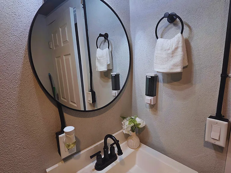 Contemporary vanity with mirror, cabinet, soap and ambient freshener.