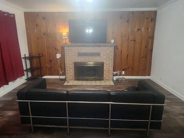 Spacious living area with wood-paneled accent wall, fireplace focal point, and open layout for comfortable seating.