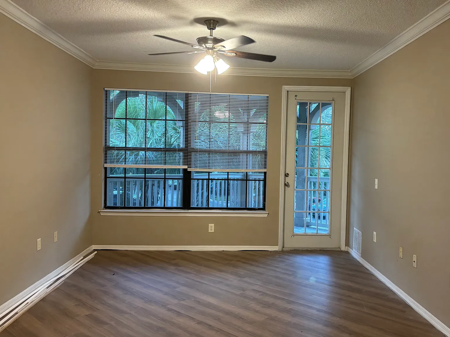 A living room entry to the balcony with a brand new ceiling fan