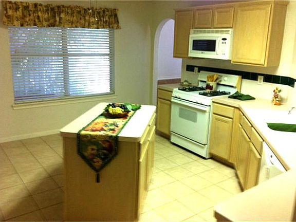 another view of island kitchen with ceramic tile flooring and gas range