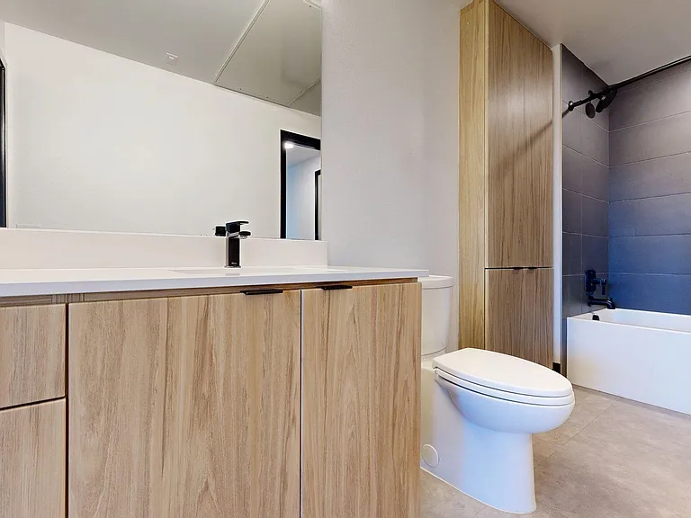 Apartment Bathroom with large soaking tub, vanity mirror and Wood-Style Flooring.