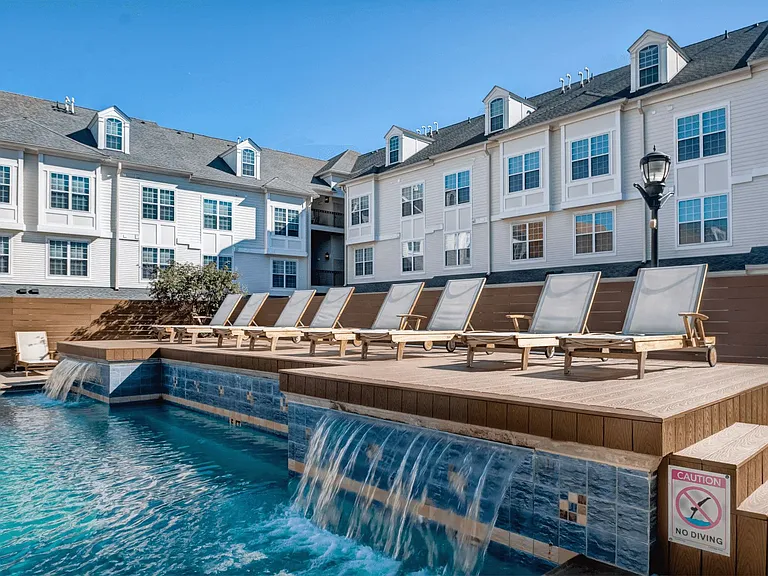 a pool with a waterfall and a row of lounge chairs at Harbor Pointe at Harbor Pointe, Bayonne, NJ, 07002