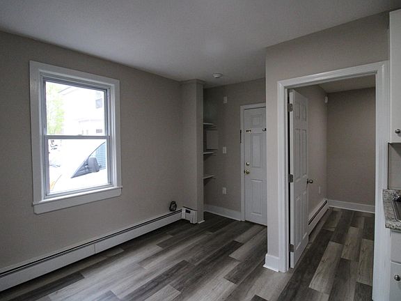 View from kitchen to entrance including in-wall shelving and door opening to bedroom