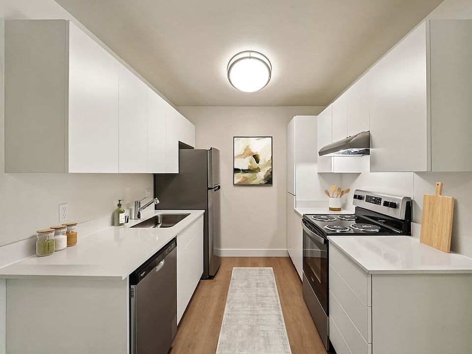 Renovated Package II kitchen with stainless steel appliances, updated white cabinetry, white quartz countertops, hard surface flooring, and updated lighting