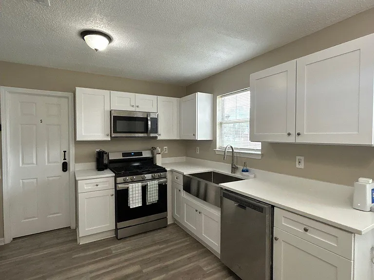 Functional kitchen with ample cabinet storage, generous counters, and stainless steel appliances plus a window over the sink.
