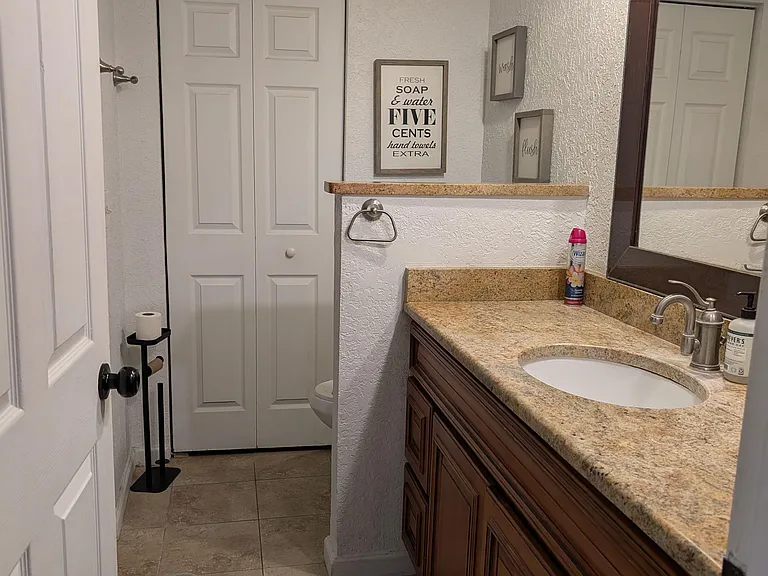 Bathroom vanity with granite-look countertop, undermount sink, and large framed mirror plus convenient linen storage.