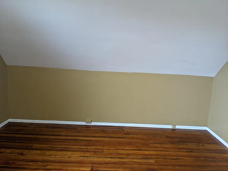 Large third floor bedroom with newly refinished hardwood floors.