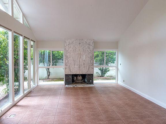 Voluminous living room of 1074 Elfstone Court, Westlake Village, CA 91361. With a view of the wide fireplace, floor-to-ceiling windows.