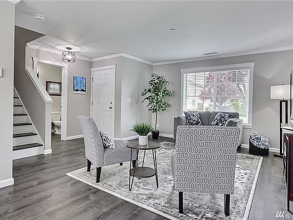 View of entry from dining room, powder room and stairs to left, sunny and airy living room. 