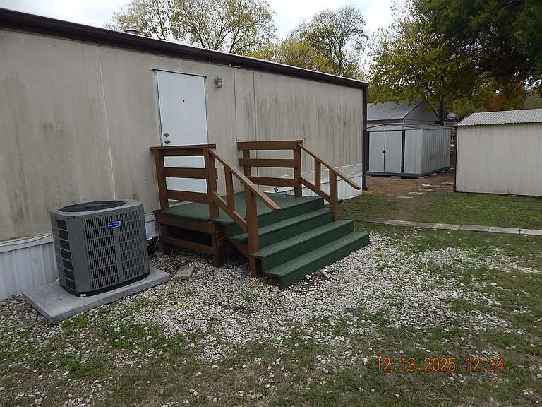 North side of home showing back deck for entrance and 2 storage sheds at back.