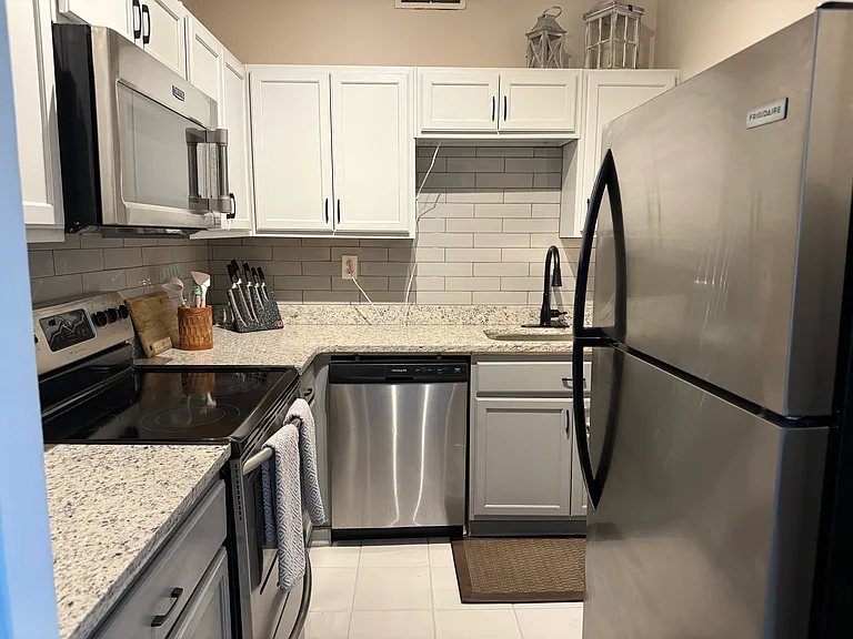 Updated kitchen features granite countertops, crisp white cabinetry, stainless-steel appliances, and a stylish subway tile backsplash.