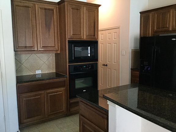 Granite counters, tile backsplash, built-in oven & microwave, large double door pantry closet visible