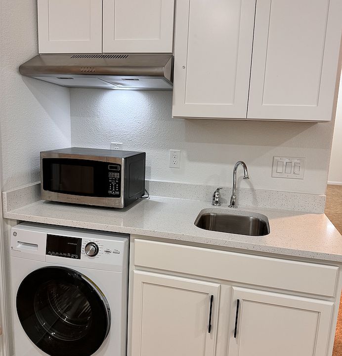 Kitchen Area with Microwave, electric stove & shelf. It has fridge and washer & dyer too.