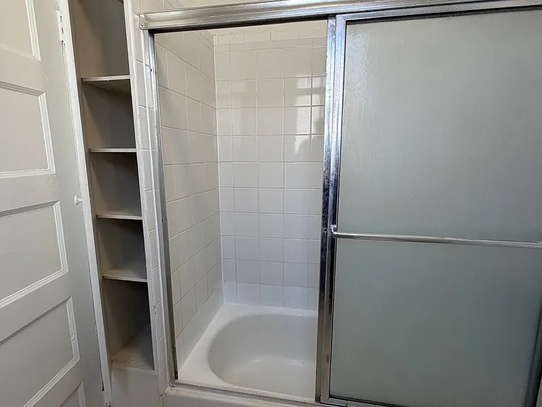Bathtub w/ shower and built in storage.