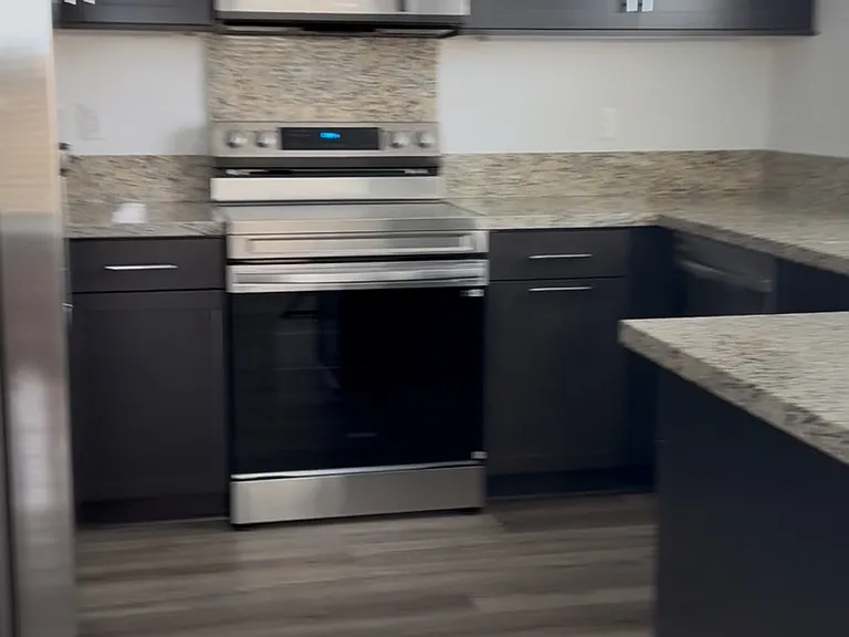 Modern Kitchen with granite countertops, stainless steel appliances & refrigerator included.