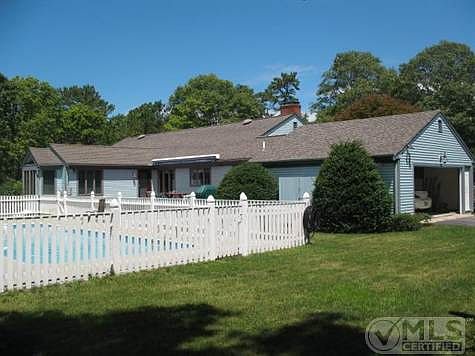 Fenced inground pool surrounded by lush lawns and mature ornamental plantings