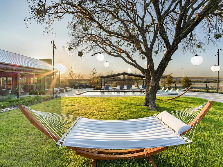 Serene poolside greens at Modera McKinney Ridge invite effortless relaxation, complete with hammocks and warm Texas sunsets.
