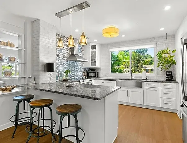 Kitchen highlighting breakfast bar, shaker cabinets, granite countertops, stainless steel sink and appliances