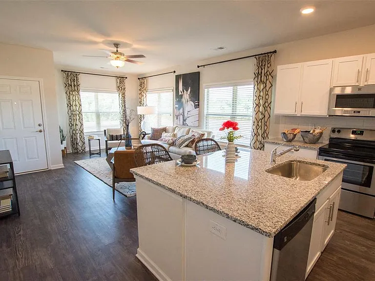 Spacious kitchen with an island, ample storage, stainless steel appliances and view into the living room.