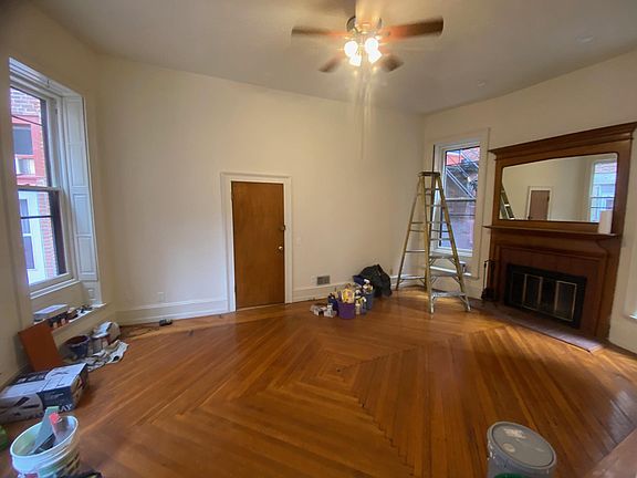 door to the unit from hallway, living room with long windows with wooden shutters on both side