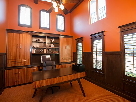 Office with custom built in, wood paneling, wood shutters