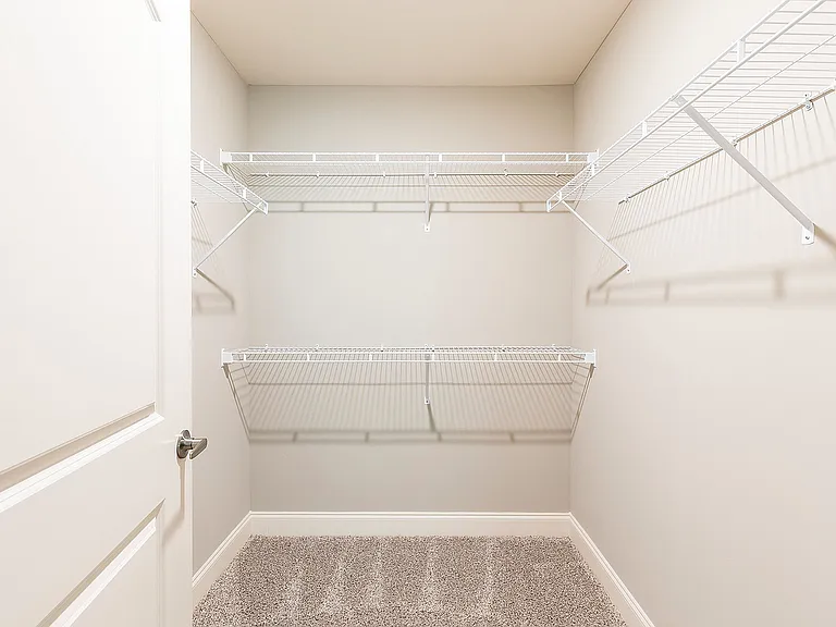 Bright walk-in closet with modern wire shelving and plush carpet, perfect for organized storage in a stylish living space.