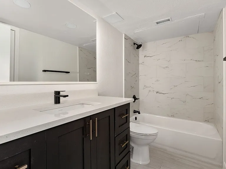 Full bathroom with toilet, vanity, wood-type flooring, and tiled shower / bath