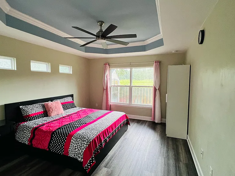 The spacious Master bedroom elegantly designed, with large windows that frame a breathtaking view of lush green landscapes