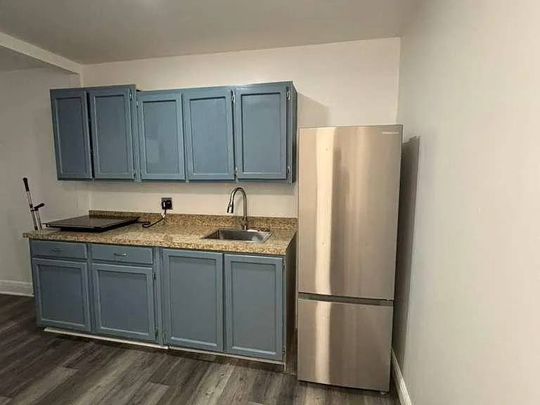 Updated kitchen with painted cabinetry, granite-look counters, stainless refrigerator, and durable wood-style flooring.