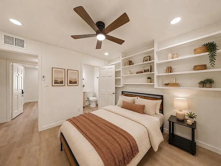Bedroom with ceiling fan, recessed lighting, and built-in wall shelving; includes bedside table and convenient nearby bath ac